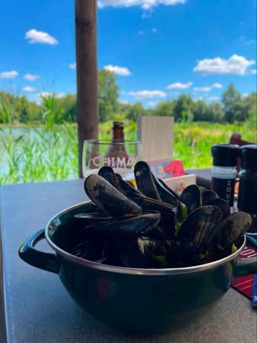 Een pot mosselen op het terras aan de vijver.